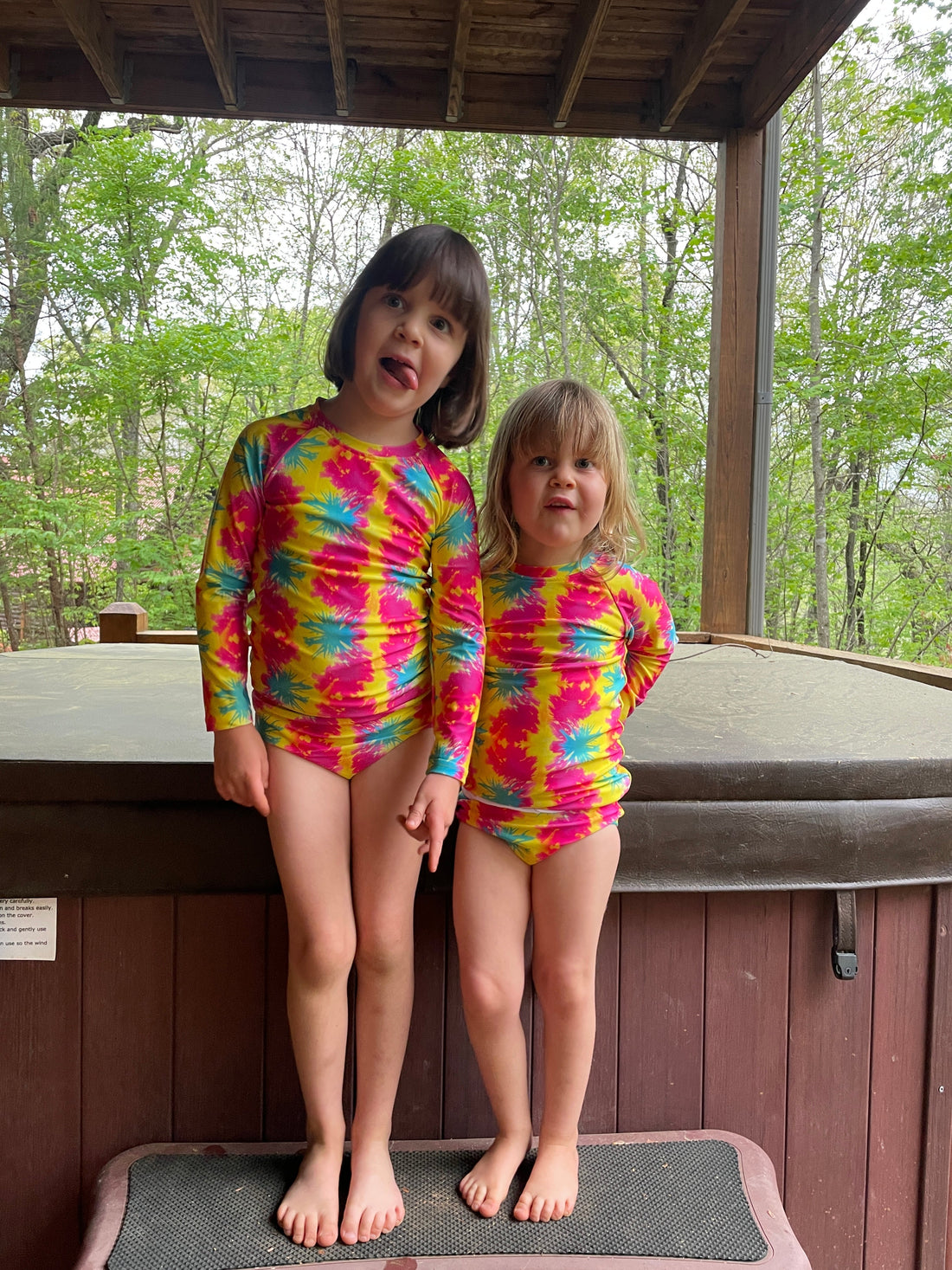 Two girls in rash guard sets in front of a hot tub