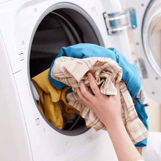 Hands putting laundry in the dryer