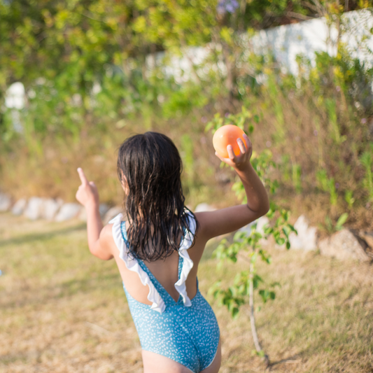 Girl in blue swimsuit throwing a water balloon