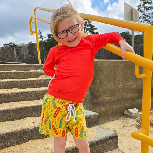 Boy in orange rash guard and yellow swim trunks